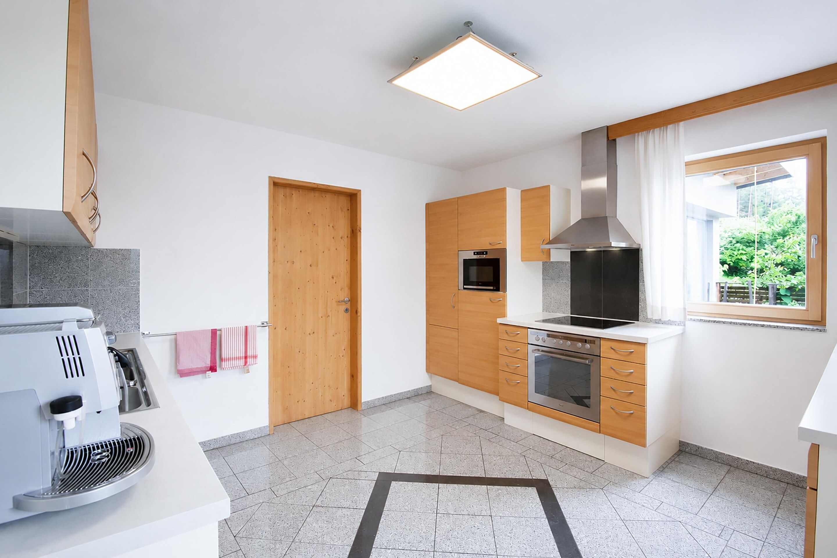 A modern kitchen with a built-in oven, microwave, and a large range hood.