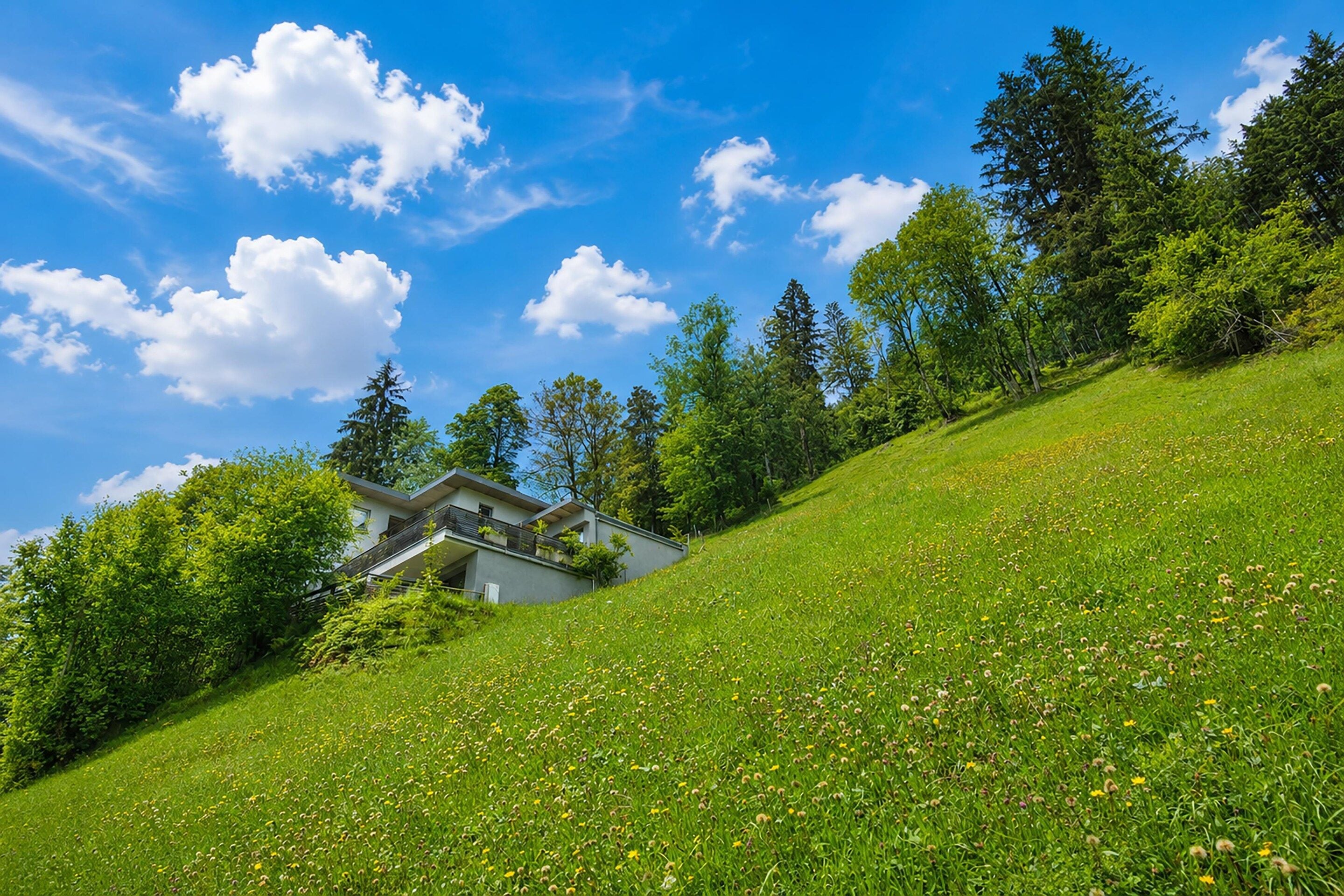 A modern house on a grassy hill with a clear blue sky.