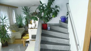 A staircase with a handrail, a living room with a sofa and a coffee table, and several potted plants. - Apartment in Aschau Near Ski Lift Kaltenbach (Aschau Im Zillertal)