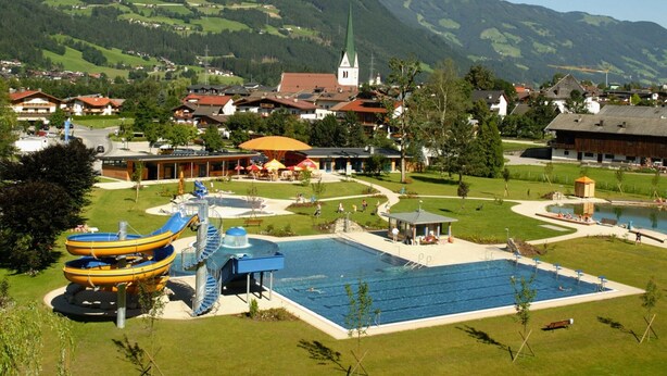 A resort with a large swimming pool, a water slide, and a view of the surrounding mountains. - Apartment in Aschau Near Ski Lift Kaltenbach (Aschau Im Zillertal)