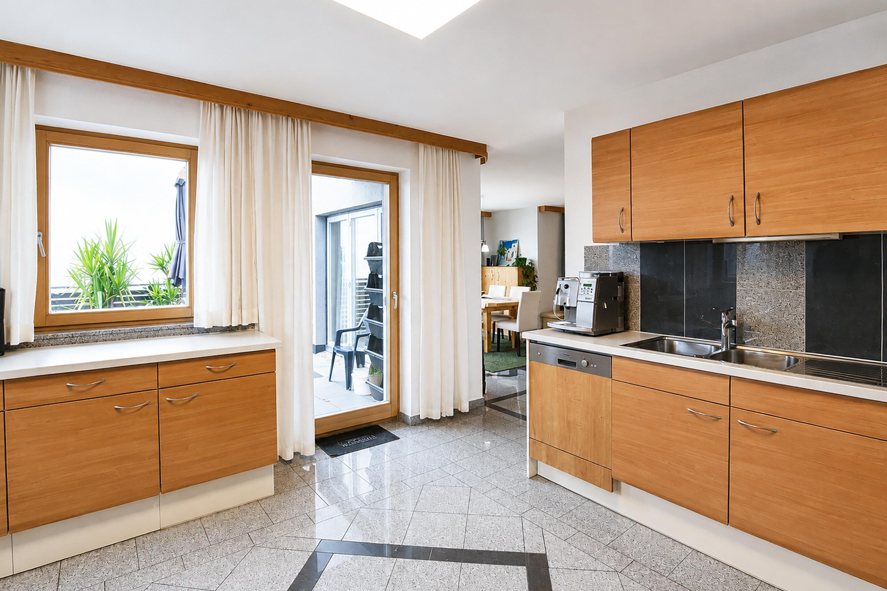 Een moderne keuken met houten kastjes, een spoelbak en een raam met gordijnen.