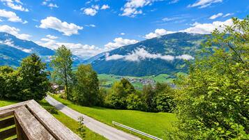 A scenic mountain landscape with a clear sky, a wooden bench, and a pathway leading through a green valley.