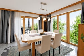 A dining area with a table set for six, large windows, and a view of greenery. - Apartment in Aschau Near Ski Lift Kaltenbach (Aschau Im Zillertal)