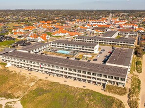 A large, modern hotel with multiple floors, a swimming pool, and a parking lot.