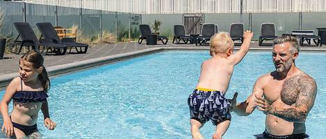 En swimmingpool med liggestole og en bygning i baggrunden.