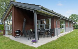 Un patio couvert aménagé avec du mobilier d’extérieur et un barbecue.