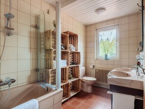 A bathroom with a bathtub, a glass-enclosed shower, a toilet, and a window with a view of greenery. - Fingerhut Comfortable Holiday Residence (Braunlage)
