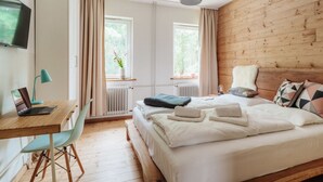 A bedroom with a wooden headboard, a bed with white linens, a desk with a laptop, a chair, and a window with curtains. - Fingerhut Comfortable Holiday Residence (Braunlage)