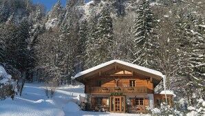 A wooden cabin with a balcony, surrounded by snow-covered trees. - Waterval in het Huis Boshoek (Aschau im Chiemgau)