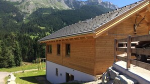 A wooden chalet with a sloped roof, large windows, and a stone foundation. - Huttenzauber 2 Comfortable Holiday Residence (Annaberg-Lungoetz)