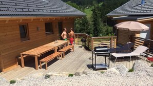 A wooden cabin with a deck, outdoor seating, and a grill. - Huttenzauber 2 Comfortable Holiday Residence (Annaberg-Lungoetz)