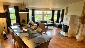 A spacious living area with a dining table, sofas, and a fireplace. - 10 Person Holiday Home in Auklandshamn (Sveio)