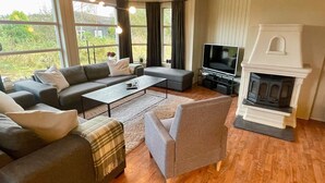 A modern living room with a sofa set, a coffee table, a TV, and a fireplace. - 10 Person Holiday Home in Auklandshamn (Sveio)