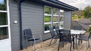 A deck with a table and chairs, a window, and a door. - 10 Person Holiday Home in Auklandshamn (Sveio)