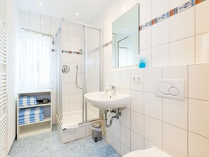 Une salle de bain avec une douche à parois de verre, un lavabo, un miroir et un porte-serviettes.