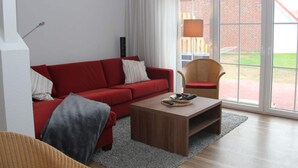 A modern living room with a red sofa, a wooden coffee table, and a wicker chair.