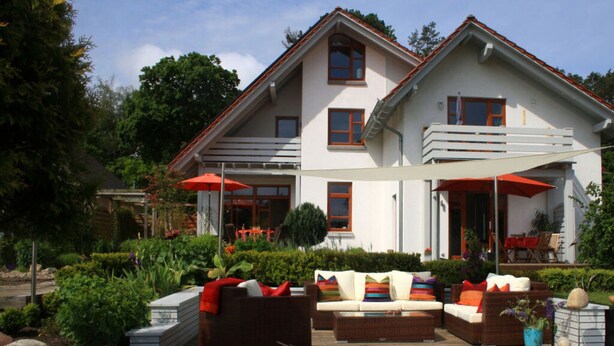 A two-story house with a patio area featuring outdoor furniture and umbrellas. - Living Lust 3 in Malchow (Malchow)