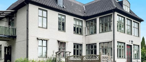 A two-story building with a brick facade, multiple windows, and a balcony.