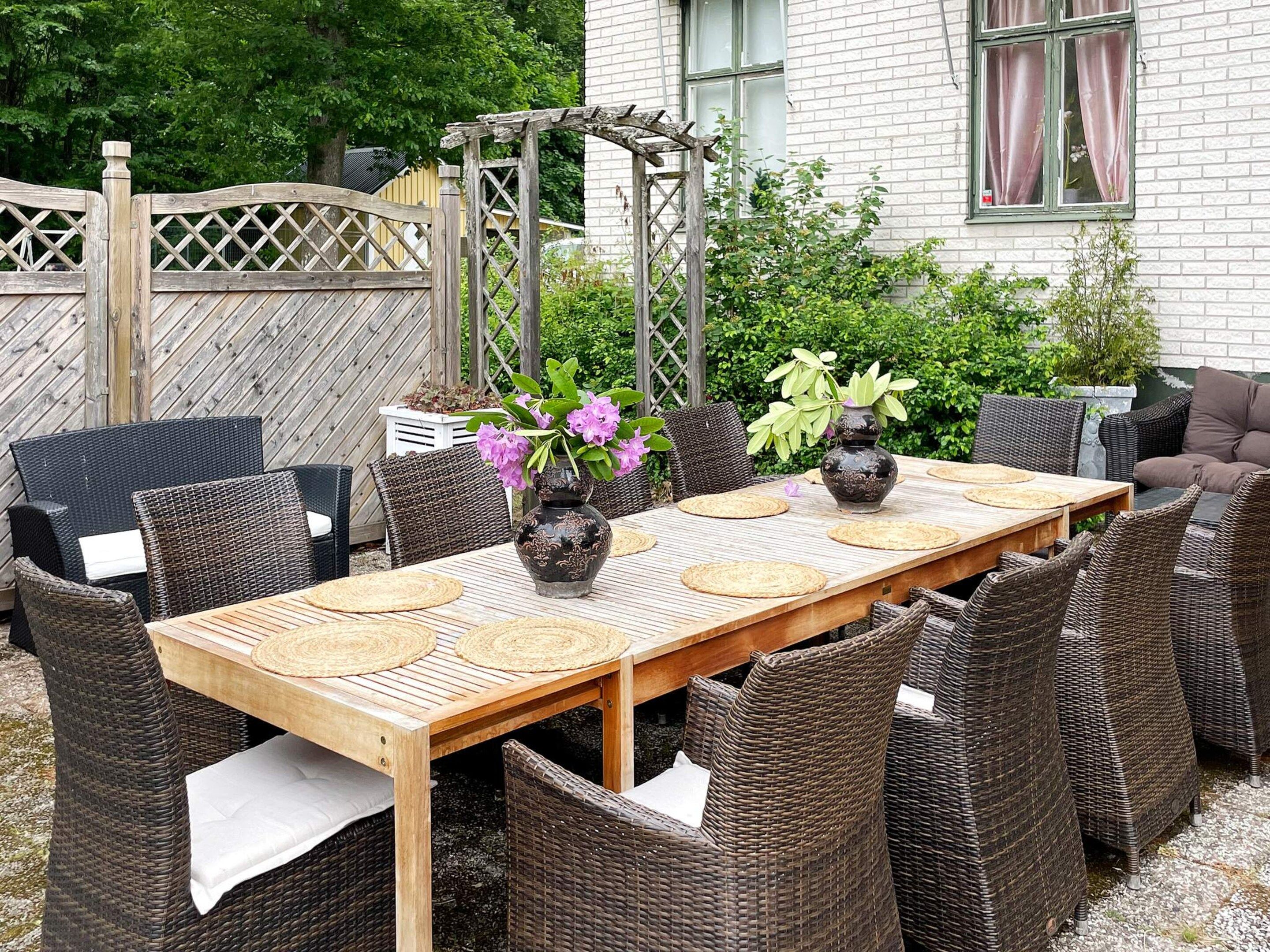 An outdoor dining area with wicker furniture, a wooden table, and decorative vases.