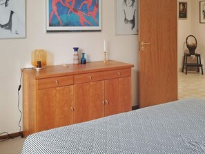 A bedroom with a bed, a wooden dresser, and artwork on the walls. - 4 Person Holiday Home in Hyltebruk (Hyltebruk)