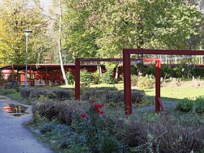 A pathway leading to a red structure with a metal frame, surrounded by greenery and trees. - 4 Person Holiday Home in Hyltebruk (Hyltebruk)