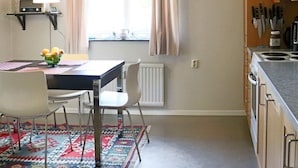 A kitchen with a dining table, chairs, a fruit bowl, and a hanging light fixture. - 4 Person Holiday Home in Hyltebruk (Hyltebruk)