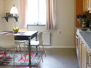 A kitchen with a dining table, chairs, a fruit bowl, and a hanging light fixture. - 4 Person Holiday Home in Hyltebruk (Hyltebruk)