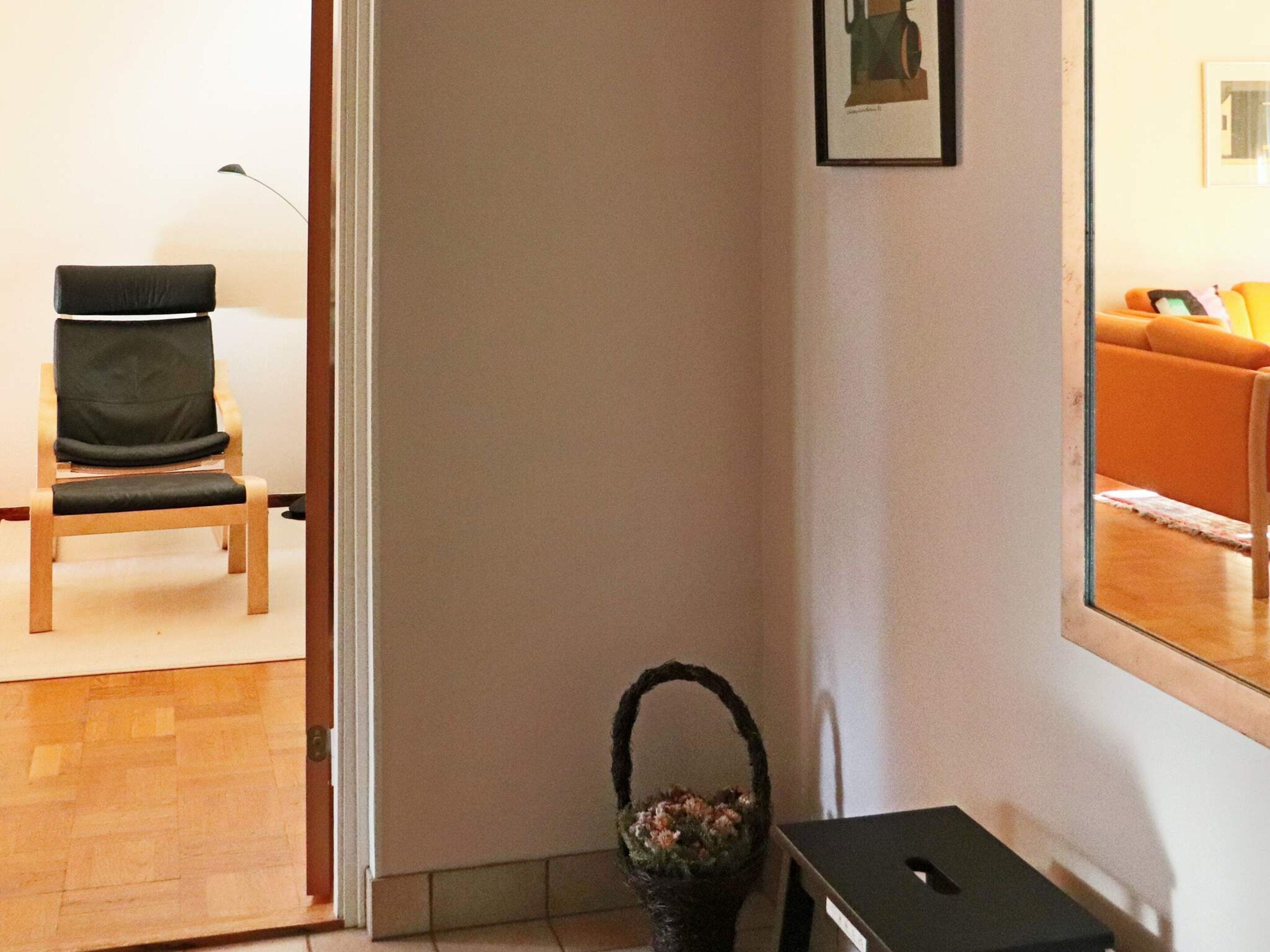 A room with a wooden chair, a small table, and a basket with flowers.