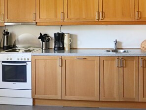 A kitchen with wooden cabinets, a Bosch stove, a coffee maker, and a sink. - 4 Person Holiday Home in Hyltebruk (Hyltebruk)