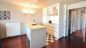 Uma cozinha moderna com uma ilha central, forno embutido e chão quadriculado em preto e branco.