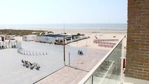 A rooftop terrace with a view of the beach, a brick wall, and a glass railing. - Apartment in Nieuwpoort With sea View (Nieuwpoort)