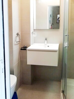 Un baño pequeño con un lavamanos blanco, un espejo y un inodoro.