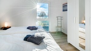 A bedroom with two beds, a window with a view of trees, and a white wardrobe. - Nitschke - Vakantiewoning Watt (Aurich)