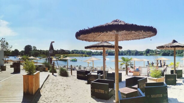A beachside area with wooden deck, thatched umbrellas, and wooden planters labeled 'SALITOS'. - Nitschke - Vakantiewoning Watt (Aurich)