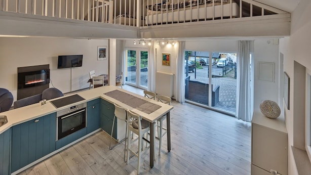 A modern kitchen with a central island, a dining area, and a staircase leading to an upper level. - Ferienhaus in Hellenthal, Eifel (Hellenthal)