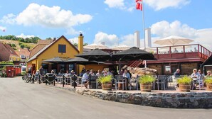 Un restaurante con terraza, paredes de piedra y una bandera.