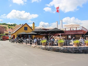Un restaurante con terraza, paredes de piedra y una bandera.
