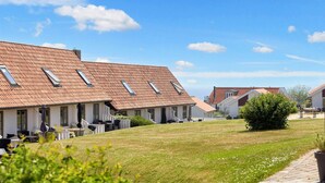En rad hus med sluttande tak och takfönster, en gräsyta och en asfalterad gångväg.