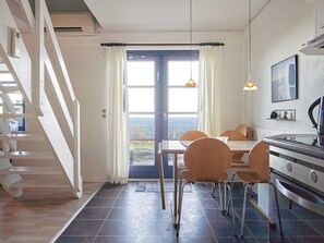 A modern kitchen with a dining area, a staircase, and a view of the sea. - 5 Person Holiday Park Home in Gudhjem (Gudhjem)