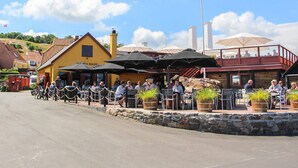 En restaurang med uteservering, en gul byggnad och en flagga.