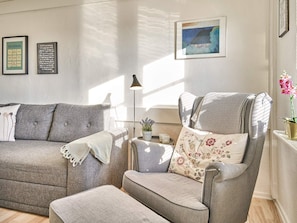 A living room with a grey sofa, a grey armchair, and a small table with a lamp and a potted plant. There are two framed pictures on the wall. - 5 Person Holiday Park Home in Gudhjem (Gudhjem)