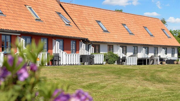 A row of single-story buildings with red-tiled roofs and multiple windows. - 5 Person Holiday Park Home in Gudhjem (Gudhjem)