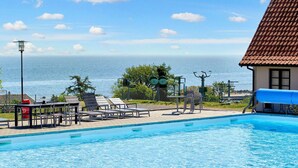 A swimming pool with lounge chairs and a view of the ocean. - 5 Person Holiday Park Home in Gudhjem (Gudhjem)