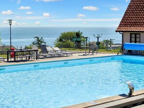 A swimming pool with lounge chairs and a view of the ocean. - 5 Person Holiday Park Home in Gudhjem (Gudhjem)