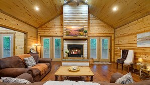 L’intérieur d’une cabane en rondins, avec une cheminée, des murs en bois, un canapé et une table à manger.