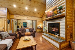 L’intérieur d’une cabane en rondins, avec une cheminée, des murs en bois, un canapé, une table basse et une table à manger.