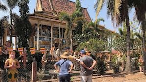 Een tempel met traditionele architectuur, een standbeeld van een godheid en een hek met vlaggen.