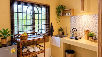 A compact kitchen with a bamboo shelf, a kettle, and a sink.