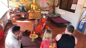 Een groep mensen in een ruimte met een groot gouden beeld, gebedsmatten en religieuze voorwerpen.