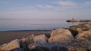 A rocky shoreline with a lighthouse in the distance.